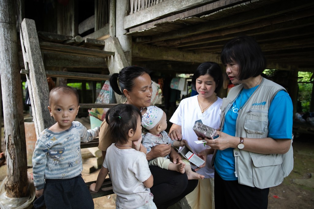 Un miembro del personal de UNICEF entrega alimentos listos para consumir a una familia en Tuyên Quang, Vietnam.